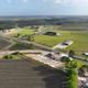 Aerial drone view of a small RV park with angled concrete pads and central building beside a highway, surrounded by