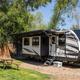 RV parked at a shaded site with picnic table and grassy area — clear depiction of an RV campsite under trees, demonstrating site spacing and surroundings from the property’s Ways to Stay photos.