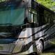 Large RV parked among trees on a gravel/grass drive — shows RV pitch and site layout; sourced from the park homepage/gallery where RV accommodations are highlighted.