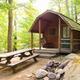 One of the cabin rentals available at the Camping Resort. This cabin has a picnic table and a wooden swing in the front.
