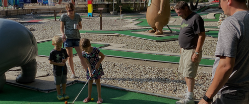 Mini golf putting area with families and park-themed sculptures — shows on-site recreation facilities (appears in site gallery/slider).