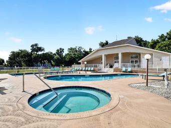 Ground-level photo of the pool area and clubhouse including hot tub and building — shows resort-style amenities and appears in the amenities gallery.