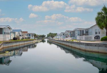 View down a canal with manufactured-home/RV waterfront sites on both sides — highlights the property’s waterfront slips and site setup (property gallery image).