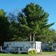 Row of RV units/long-term sites on a grassy pad showing site layout and typical RV accommodation — supports the rates/reservations page imagery.
