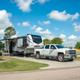 Ground-level photo of a full-hookup RV site with truck and picnic table — useful for showing campsite setup and space available.