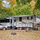 RV site pictured with a large fifth-wheel, fire ring and seasonal foliage — good example of typical RV camping spaces on property (‘ways to stay’ image).