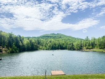 Wide view of the campground’s lake with dock and tree-lined shore — useful scenic overview of on-site water recreation shown in site imagery.