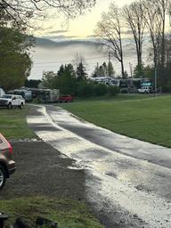 Morning/fog scene down an internal road with multiple RVs visible and campground lawn — useful atmospheric view of RV pitches and site layout (source: homepage/gallery).