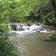 A waterfall with lush greenery surrounding it during the summer