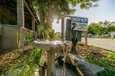 Foreground garden fountain with RVs and parking visible in background — shows landscaping/detail plus nearby RV spaces on the property (gallery page).