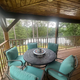 Covered deck seating looking out to wooded grounds and water — shows guest outdoor space and relationship to the pond/grounds.