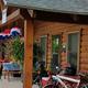Front porch of a log/cedar cabin with outdoor seating and bikes — clear view of guest lodging and amenities (file from the site showing decorated cedar cabin).