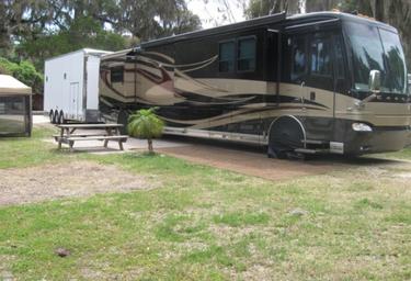 Ground-level view of an RV on a site with picnic table and pad — depicts the campground's RV accommodations and site setup.