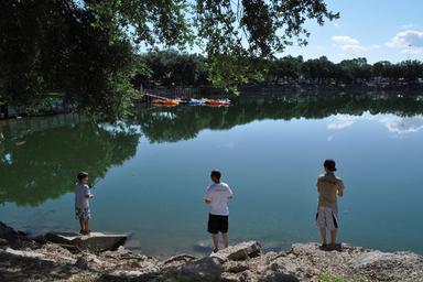 View of the park lake with paddle boats and people fishing — depicts on-site recreation and waterfront activities referenced on the activities section.