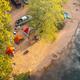 Top-down drone shot of riverside tent camping on a gravel beach, showing tent layout and river access; matches river/camping content from the site.