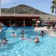 Outdoor pool area with lounge chairs, covered patio and visible property fencing/hill behind — clearly shows the campground’s pool facility (source page: Activities).