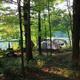 Tent camping area set among trees with a view toward water — depicts wooded tent sites and nearby natural scenery indicated on the campground’s page.