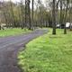 Gravel access road winding through tree-lined campsites with RVs visible in the distance — from the trailer-camp-sites page, useful to show internal roads and campsite arrangement.