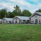 Wide, high-quality photo showing the row of four lakefront cabins and open lawn — clear overall view of the cabin accommodations and shoreline (matches property homepage cabin images).