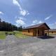 Clear exterior view of an individual cabin with porch, picnic/firepit area and open lawn — useful for showing unit exterior and outdoor seating/firepit setup.
