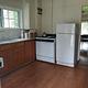 A kitchen with sink, refrigerator, propane stove, and hardwood floor.