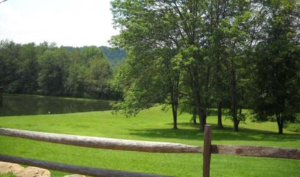 Open grass area with a pond and fence — shows on-site water feature and scenic grounds (About page imagery of property landscape).