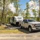 RV campsite with truck and trailer, picnic table, grill and wooded setting — shows typical RV/tent site setup on the property.