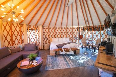 Bright, well-staged interior shot of a yurt main room (bed, seating, dining) — excellent for showcasing the furnished luxury yurt interior; appears on the site’s main yurt listing pages.