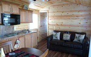 Interior view of a cabin (Cedar Lodge) showing kitchen and living area — matches gallery page listing cabin accommodation on the campground site.