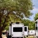 View of RV pads with a parked travel trailer (Astoria) under trees, showing typical RV pitch layout and spacing on the property (from Home/Gallery).