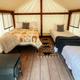 Interior view of a tent showing bedding, wood floor and stove — demonstrates the furnished glamping interior and sleeping arrangements.