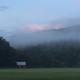 Wide scenic view with mist/fog over open fields and a distant barn — gallery image that captures campground surroundings and atmosphere.