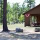 Covered event pavilion with picnic tables, skyline of campground trees and lawn — clear image of a named on-site facility (listed under amenities on the website).