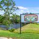 Freestanding Shady Lake RV Park sign next to the lake and roadway — identifies the property and provides context of lakeside location (About Us / site imagery).