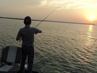 A young man fishing at sunset