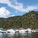 Boats in dock slips in a marina with a mountain of red rock and trees in the background.