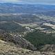 Looking down on green grass and forest covered ridge lines from a rocky high point.