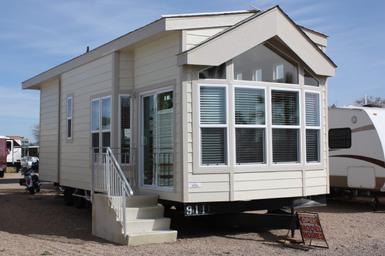 Model park home on gravel pad with adjacent RV visible — useful for showing available accommodations and site appearance (source page: Rates).
