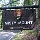 Outdoor wooden sign labeled "Misty Mount" with an arrow symbol.