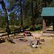 A picnic table, benches, and a fire ring next to a rustic cabin.