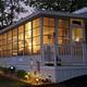 Exterior evening view of a lakeside cottage with lit windows and landscaped yard — good to illustrate rental cottage accommodations (file shown on the site’s main page for the property).