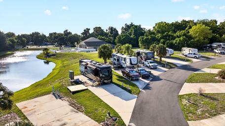 Drone image of RV pads and adjacent pond with several rigs visible — clear view of typical RV sites and onsite water features; originates from the 'plan your stay' page.