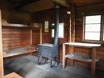Sergief Island Cabin interior showing wood bunkbeds, shelves and stove