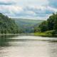 Wide river landscape view showing the Delaware River flanked by wooded hills — good scenic overview used on the property homepage to represent the campground’s riverfront setting (page context: main site imagery).