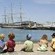 Five young children sit on the beach on a July afternoon at Aquatic Park Cove, San Francisco.