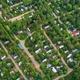 Aerial view of a residential area surrounded by trees and a small lake.