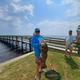 Daytime pier/shoreline photo showing a catch and the pier in the background with grassy shoreline — useful to illustrate on-site waterfront recreation and pier access.  