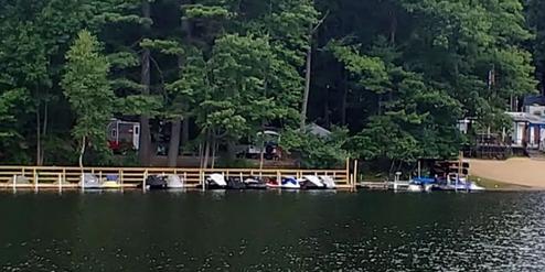A row of jet skis docked on a lake with a forested background.