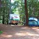 Close view of a numbered tent/RV campsite (site #5) among trees, demonstrating individual campsite layout and setting on the property.