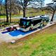 Aerial/angled view of a riverside RV pad with motorhome, gravel parking pad, picnic table and the Frio River visible behind — strong overview of riverfront RV sites from the property gallery page.